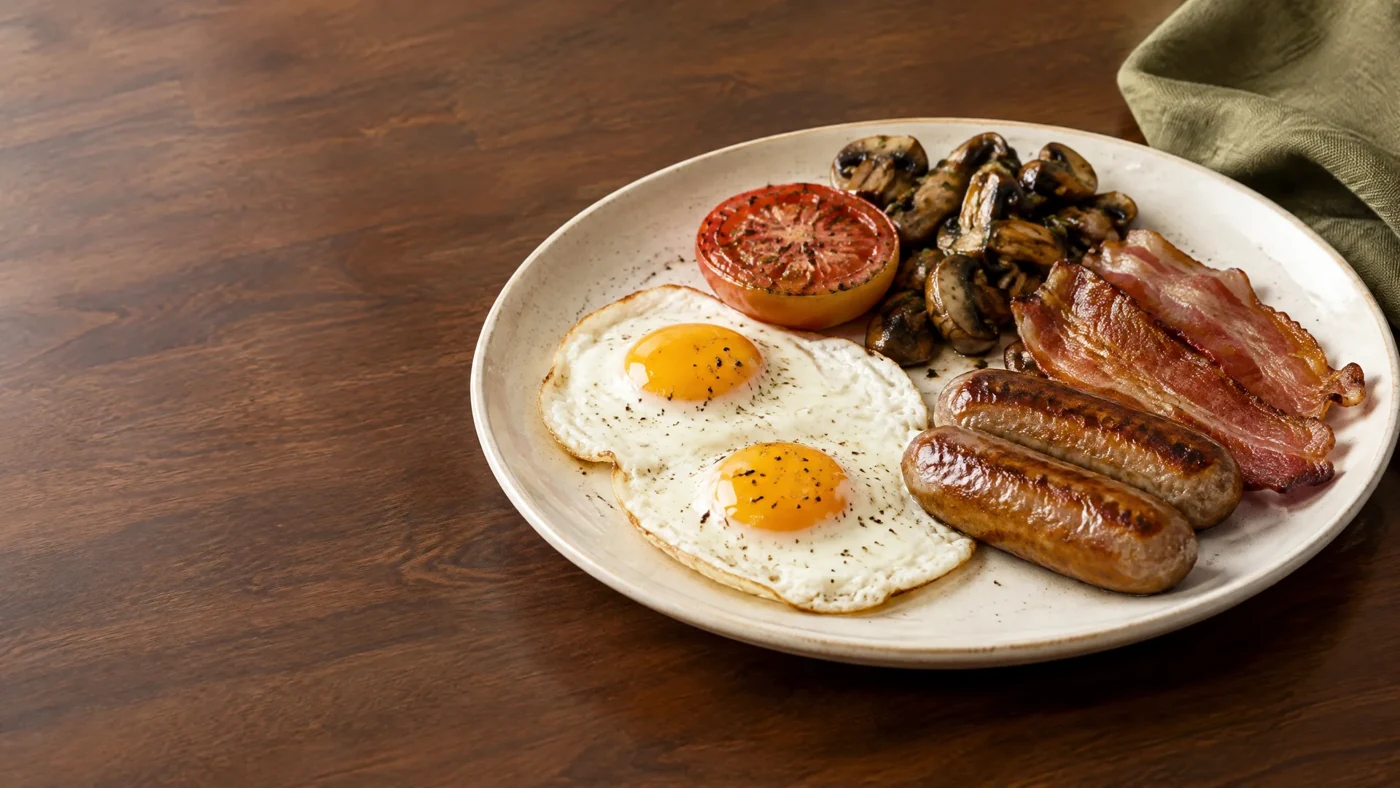 A British brunch with eggs, sausages, bacon, mushrooms and tomato
